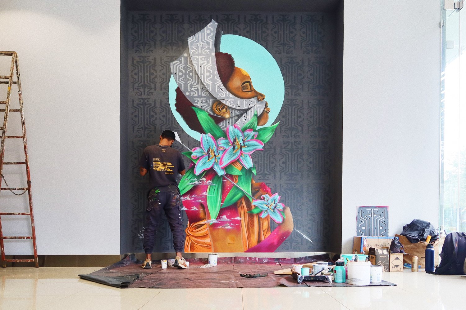 WiseTwo (artist) painting a mural of a beautiful tribal lady with colourful flowers