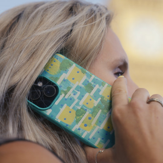 Person holding a Kusudi phone case with a colorful case against a blurred background